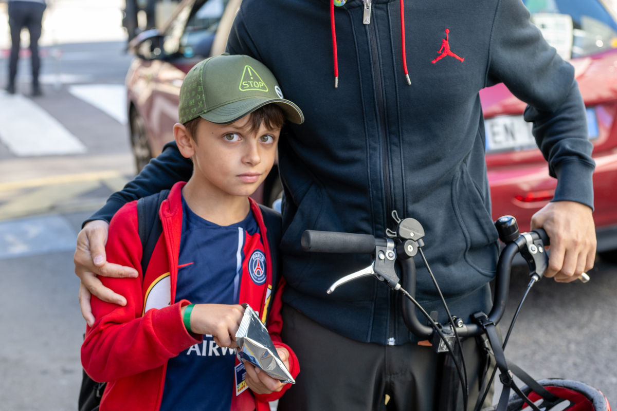 Bambino con bicicletta davanti alla scuola
